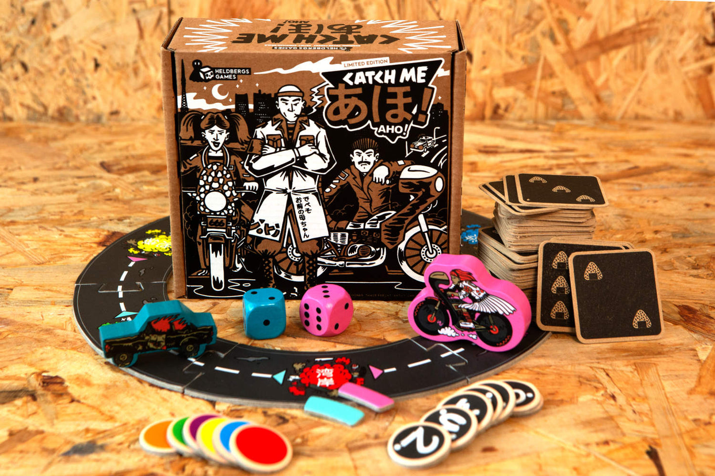 Die Frontansicht der Verpackung und des Spielbretts von „Catch Me Aho“ zeigt die kultigen Illustrationen und Designelemente, die die Straßen Tokyos und das Leben der Bōsōzoku-Banden stilvoll darstellen. Die siebgedruckte Box sowie die liebevoll gestalteten Spielkarten und -figuren vermitteln den Charme und die Atmosphäre der japanischen Speed Tribes und bringen ein Stück der Straßenkultur ins Wohnzimmer.